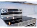 Close-up of a modern stainless steel electric stove top, set into bright countertops with hexagon tile backsplash at 506 St Johns Ct, Poinciana, FL 34759