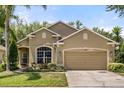 Inviting single-story home with a well-kept lawn, flowering shrubs, and an attached two-car garage at 9644 Myrtle Creek Ln, Orlando, FL 32832