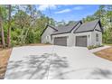 Spacious two-car garage with gray doors, exterior lights, and a long concrete driveway at 1394 Kettledrum Trl, Deltona, FL 32725