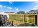 Backyard view showing black metal fence, green space and neighboring townhomes beyond at 1401 Mirabella Cir, Davenport, FL 33897