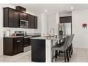 Modern kitchen with dark cabinets, granite countertops, stainless steel appliances, and island seating for four at 1401 Mirabella Cir, Davenport, FL 33897