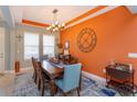 Stylish dining room featuring a large dining table with seating, modern chandelier, and decorative orange accent wall at 14830 Winkfield Ct, Winter Garden, FL 34787