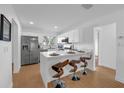 Open-concept kitchen with a breakfast bar, stainless steel appliances, and modern white cabinetry at 4901 Lindsay Ct, Orlando, FL 32821