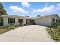 Low-angle view of a charming one-story home with a wide driveway and manicured landscaping at 6327 Ridgeberry Dr, Orlando, FL 32819