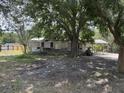Exterior view of home with screened porch, mature trees, and overgrown yard at 749 Saddlewood Blvd, Lakeland, FL 33809