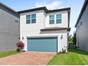 Two-story home featuring a teal garage door, brick driveway, and neat landscaping at 9425 Holliston Creek Pl, Winter Garden, FL 34787