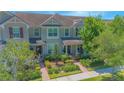 View of the townhome featuring a charming facade, manicured lawn, and red brick walkway at 10520 Burrows St, Orlando, FL 32832