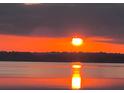 A picturesque view of a vibrant sunset reflecting over the calm lake waters at 10845 Bayshore Dr, Windermere, FL 34786