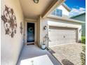 View of the front porch with artistic wall decor, a small potted plant, and a two-car garage at 11868 Thatcher Ave, Orlando, FL 32836