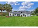Expansive green backyard featuring a well-maintained lawn, lush landscaping, and the home's rear facade at 12508 Lake Denise Blvd, Clermont, FL 34711
