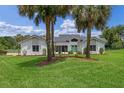 Charming home exterior showcasing a lush lawn, mature palm trees, and a welcoming turquoise front door at 12508 Lake Denise Blvd, Clermont, FL 34711