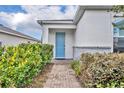 Inviting front entrance features a bright blue door and well-maintained landscaping at 14325 Hidden Ct, Clermont, FL 34711