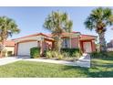 Beautiful single-story home featuring tropical landscaping, a red tile roof, and an attached two-car garage at 156 Carrera Ave, Davenport, FL 33897