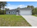 Single-story home featuring a two-car garage, gray exterior and a well-kept lawn at 16904 Sw 30Th Avenue Rd, Ocala, FL 34473