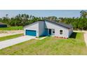 A modern home showcasing a gray exterior, a blue garage door, and a well-maintained lawn at 17434 Sw 36Th Avenue Rd, Ocala, FL 34473