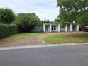 View of a well-maintained home with a brick driveway and lush landscaping, including mature trees and manicured hedges at 1773 Walnut Ave, Winter Park, FL 32789