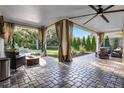 Covered patio with stone flooring, elegant drapes, and comfortable seating overlooking the pool at 190 Osprey Hammock Trl, Sanford, FL 32771