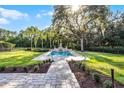 Backyard features a luxurious pool and fountain, surrounded by lush greenery and palm trees at 190 Osprey Hammock Trl, Sanford, FL 32771