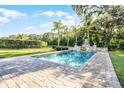 A stunning rectangular pool with a stone waterfall, complemented by mature trees and a manicured yard at 190 Osprey Hammock Trl, Sanford, FL 32771