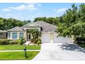 Beautiful single-story home with a lush green lawn, a three-car garage, and verdant landscaping at 2026 Winding Oaks Dr, Orlando, FL 32825