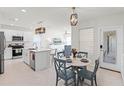 Modern kitchen with white cabinets, stainless steel appliances, an island with quartz countertops, and an adjacent dining area at 4063 Roaming Brook Dr, Apopka, FL 32712