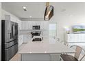 Bright kitchen features white cabinets, stainless steel appliances, and a large island with quartz countertops at 4063 Roaming Brook Dr, Apopka, FL 32712