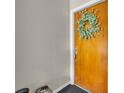 A close up of a stained wood front door decorated with a leafy green wreath and with gray walls at 4306 Lake Underhill Rd # C, Orlando, FL 32803