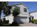 Two-story home with two-car garage, brick paver driveway, set amongst mature landscaping and green grass at 8926 Zurich Ln, Kissimmee, FL 34747