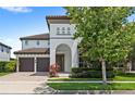 Two-story home featuring a brown tile roof, a two-car garage, a brick driveway, and lush landscaping at 11707 Hampstead St, Windermere, FL 34786
