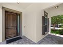 Charming front porch features a wooden door with a glass pane, brick flooring and a window with dark shutters at 11707 Hampstead St, Windermere, FL 34786