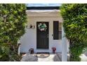 Inviting front door adorned with a wreath, flanked by manicured shrubs and vibrant potted plants at 1216 Floral Way, Apopka, FL 32703