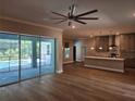 Spacious living room showcasing sliding doors, hardwood floors, and an open floor plan leading to kitchen at 160 Steeplechase Cir, Sanford, FL 32771