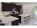 Modern kitchen with dark cabinets, stainless steel appliances, and center island with barstool seating at 1901 Fulfillment Dr, Kissimmee, FL 34744