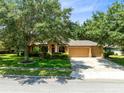 Inviting single-story home with a three-car garage, surrounded by lush landscaping and mature trees at 24720 Calusa Blvd, Eustis, FL 32736