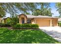 Well-maintained single-story home features a landscaped lawn, a blue front door, and an attached three-car garage at 24720 Calusa Blvd, Eustis, FL 32736