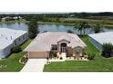 Aerial view of a lovely single-story home with a well-manicured lawn, lush landscaping, and a serene lake view at 27143 Nostalgia Dr, Leesburg, FL 34748