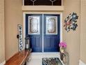 Elegant double front doors with decorative glass, complemented by charming welcome decor and a cozy bench at 27143 Nostalgia Dr, Leesburg, FL 34748