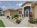 Inviting single-story home featuring a manicured front yard with decorative landscaping and an arched entryway at 27143 Nostalgia Dr, Leesburg, FL 34748