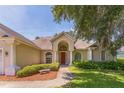 Welcoming single-level home with a red front door, manicured bushes, and ample natural light at 34239 Woodridge Ln, Eustis, FL 32736