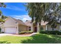 Inviting single-Gathering home showcasing a red front door and a lush green yard with mature trees at 34239 Woodridge Ln, Eustis, FL 32736