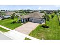 Aerial view showcases a gray single-story home, 3-car garage, a charming porch and a well-maintained lawn at 3630 Trimaran Dr, Orlando, FL 32820