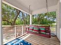 Inviting porch with a comfortable swing adorned with colorful pillows and a beautiful outdoor view at 485 Palm St, Winter Garden, FL 34787