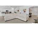 Bright open-concept living space with a white leather couch and modern finishes adjoining the kitchen at 6013 Mount Zion Cir, Deland, FL 32724