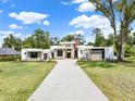 Modern home with stone accents and a long driveway, set on a well-maintained lawn under a blue sky at 7615 Se 12Th Cir, Ocala, FL 34480
