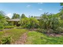 A view of the side of the home, with a lush, manicured lawn with mature trees and landscaping at 98 Wisteria Dr, Longwood, FL 32779