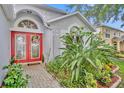 Close up of front entrance with double red doors, brick paver walkway and lush tropical foliage at 1181 Welch Hill Cir, Apopka, FL 32712