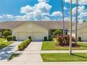 Inviting single-story home with attached garages, green landscaping, and a well-manicured front yard at 130 Club Villas Ln, Kissimmee, FL 34744