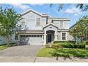 Charming two-story home showcasing lush landscaping and a paver driveway at 1520 Mulligan Blvd, Davenport, FL 33896