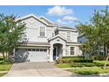 Charming two-story home showcasing lush landscaping and a paver driveway at 1520 Mulligan Blvd, Davenport, FL 33896