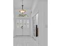 Inviting foyer featuring a decorative light fixture, white tile flooring, and double front doors at 4905 Emilee Grace Ln, St Cloud, FL 34771